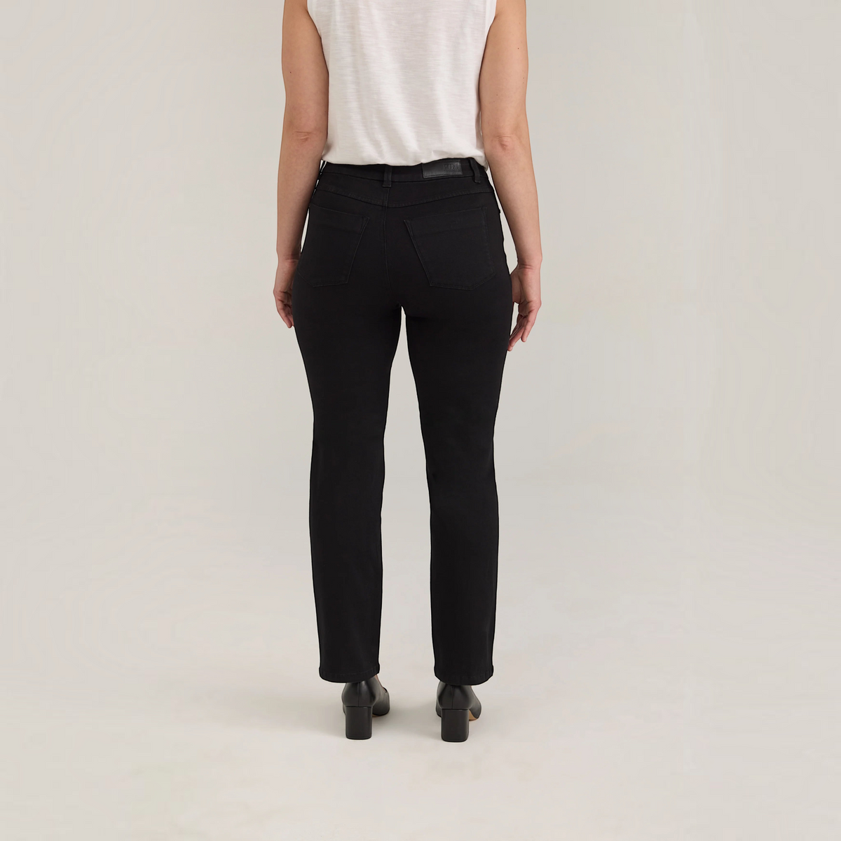 Back view of Plum Bottom FDJ Olivia petite straight leg jeans in black onyx denim worn with a white top and heels