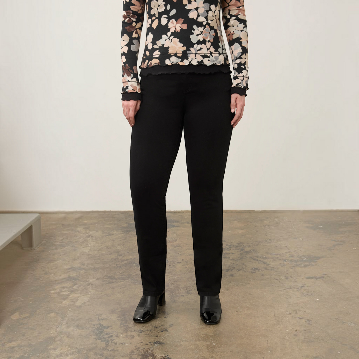 Plum Bottom FDJ Suzanne straight leg jeans in black worn with a floral long-sleeve top and black block-heel boots.