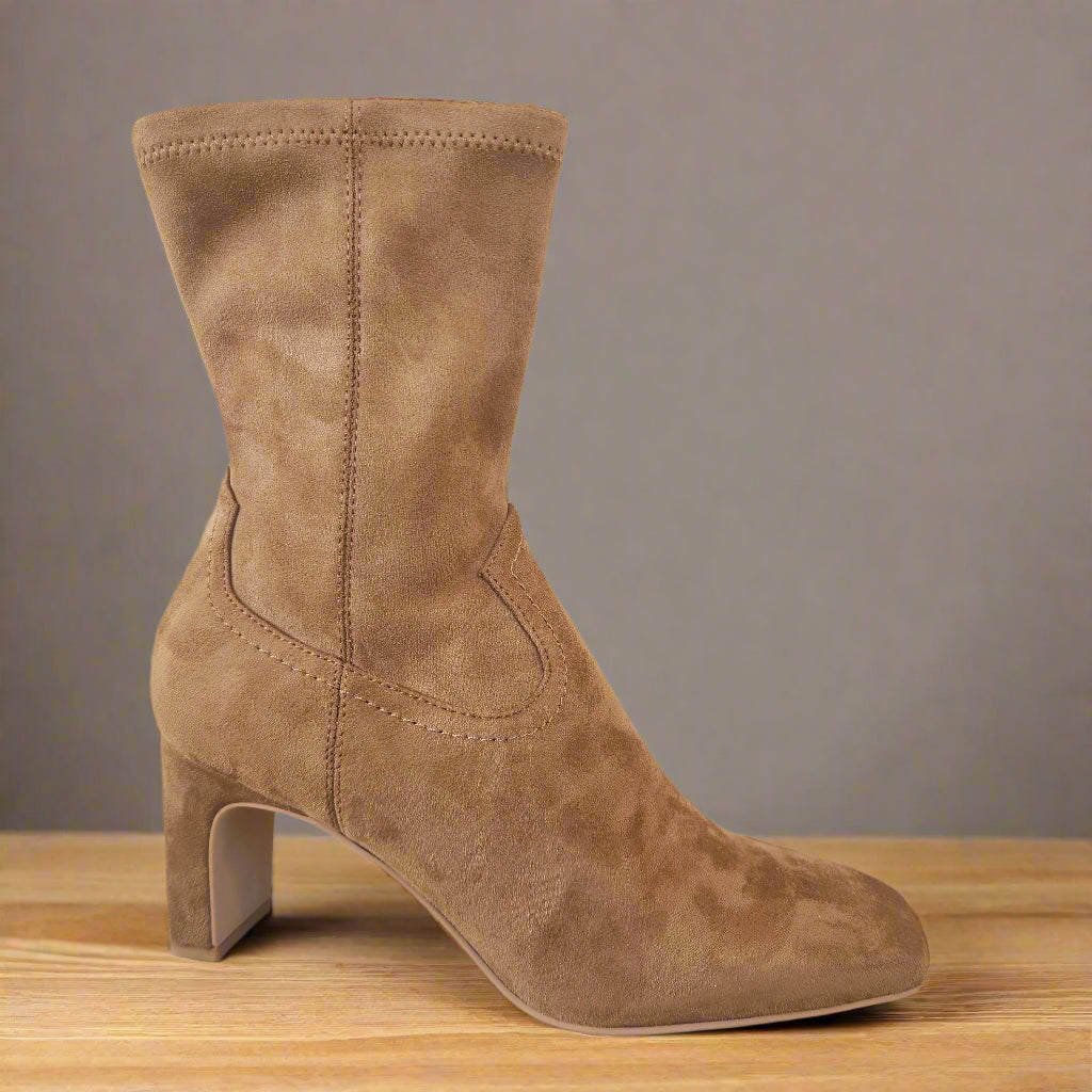 Brown suede ankle boot on a light tiled floor