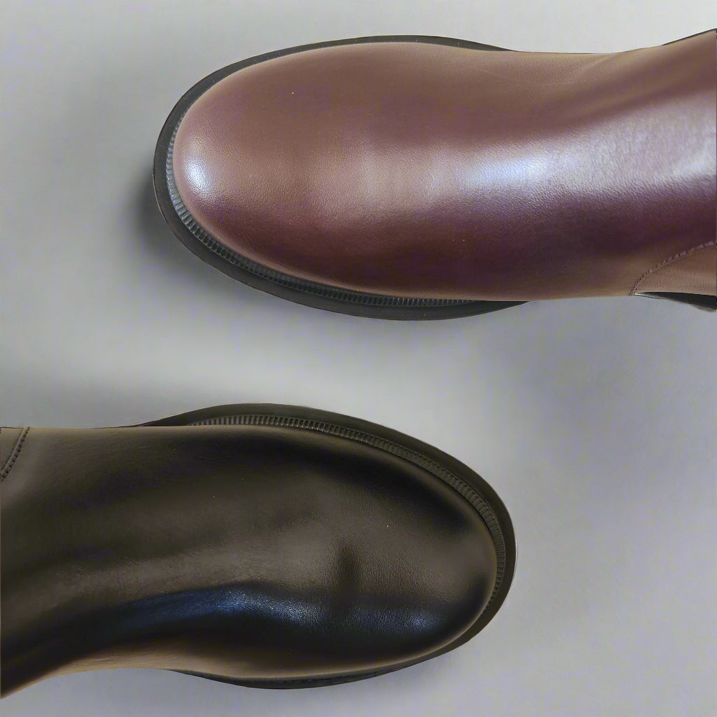 Brown and black leather boots on a textured surface