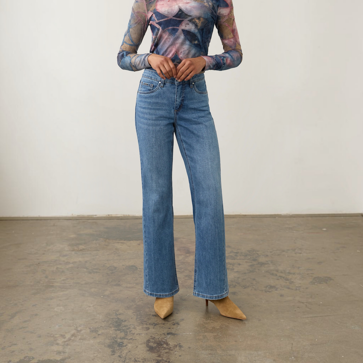 Plum Bottom FDJ Olivia bootleg jeans in medium wash denim worn with a patterned long-sleeve top and tan heels.