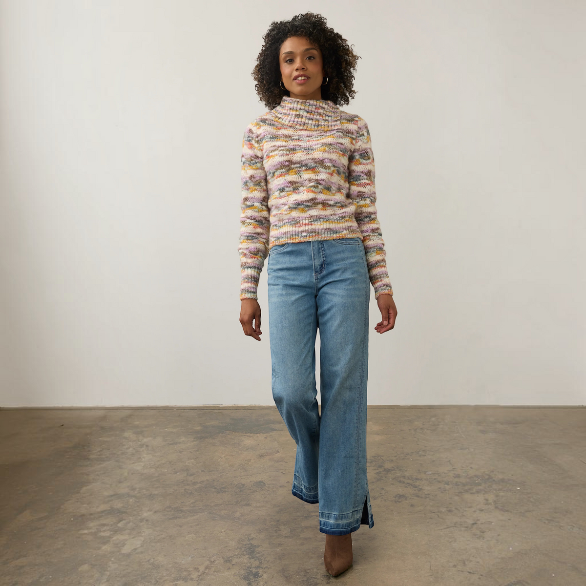 Model wearing a Plum Bottom FDJ envelope collar sweater with a multi-colored space dye knit pattern and blue jeans.