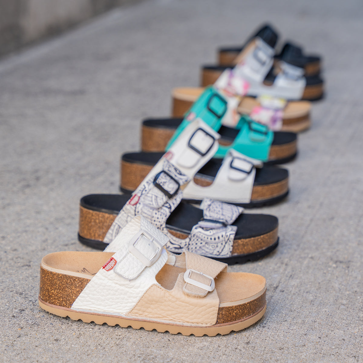 Row of platform sandals with two straps and a buckle in a wide variety of colors