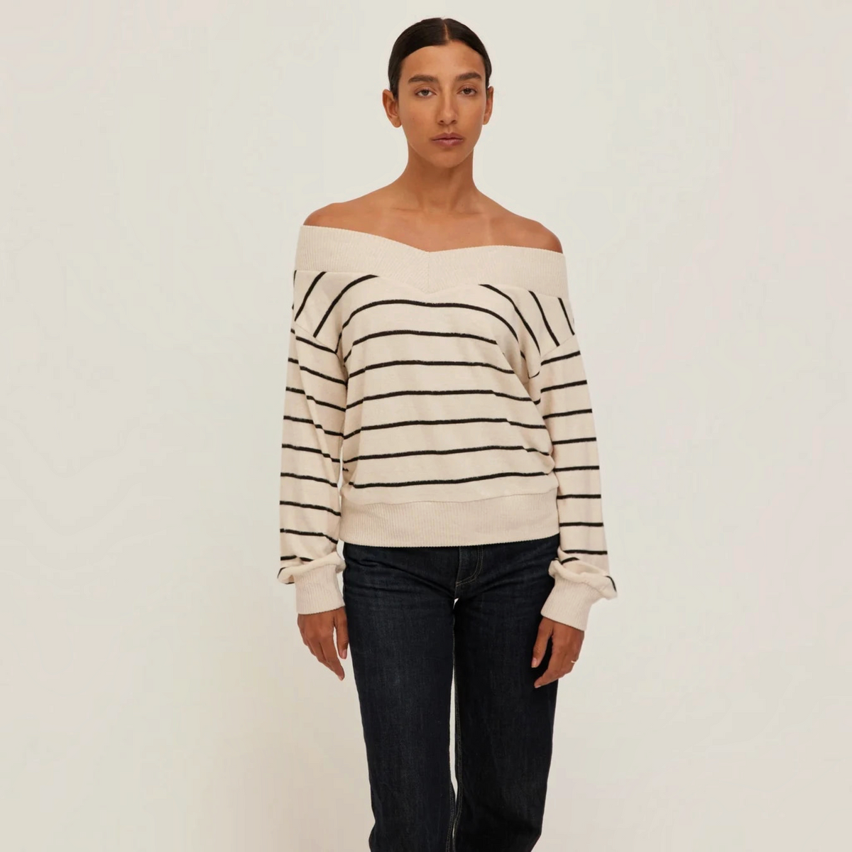 Plum Bottom Carmel Pullover in cream and black stripes with an off-shoulder neckline worn by a model