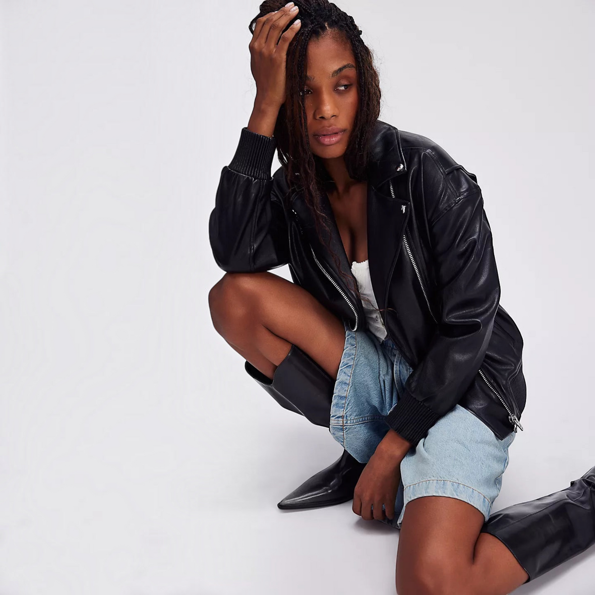 Plum Bottom model wearing a black BLANK NYC vegan leather moto jacket with ribbed trim and asymmetrical zip closure.