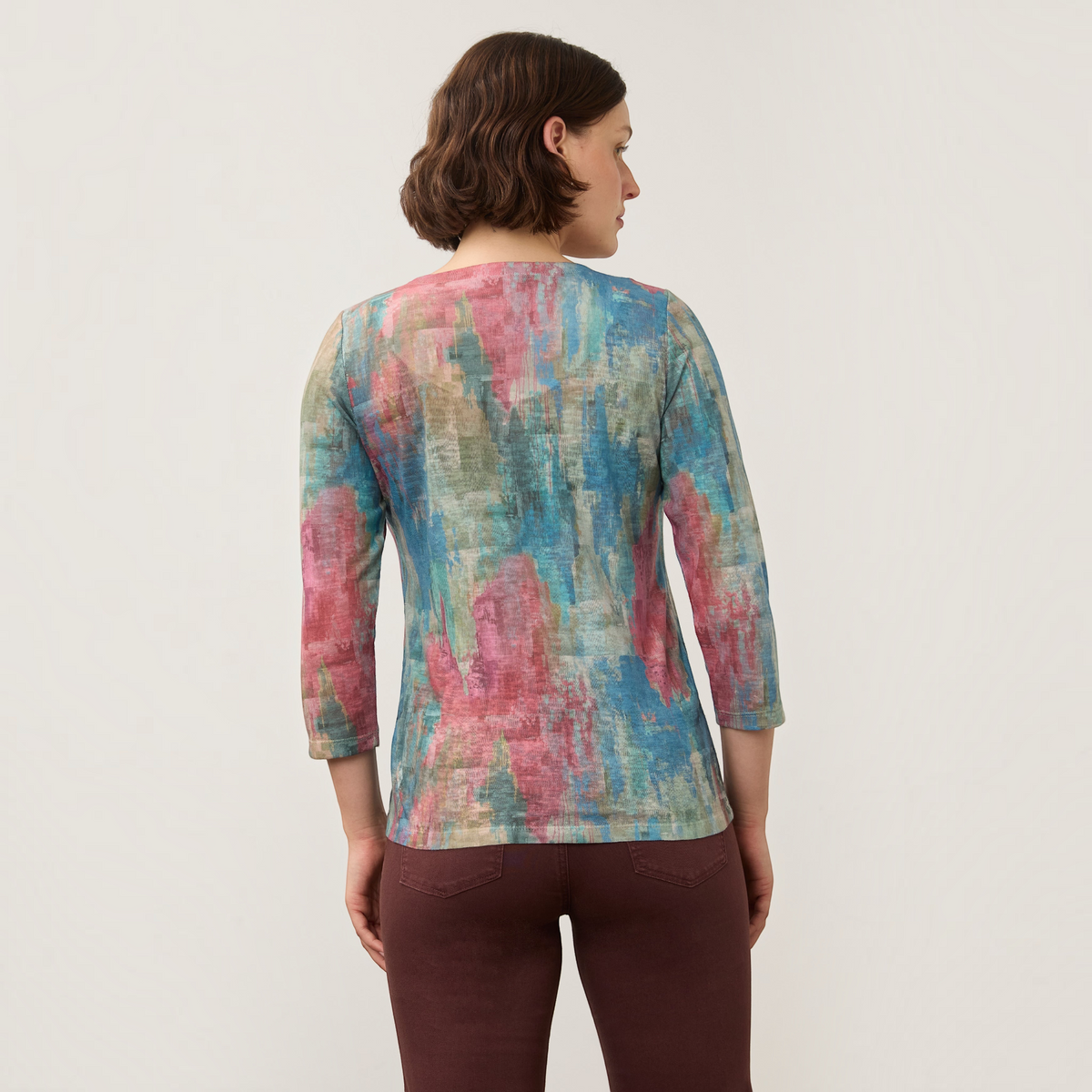 Back view of a woman wearing a Plum Bottom FDJ notch neck top with a multicoloured abstract print and three-quarter sleeves.