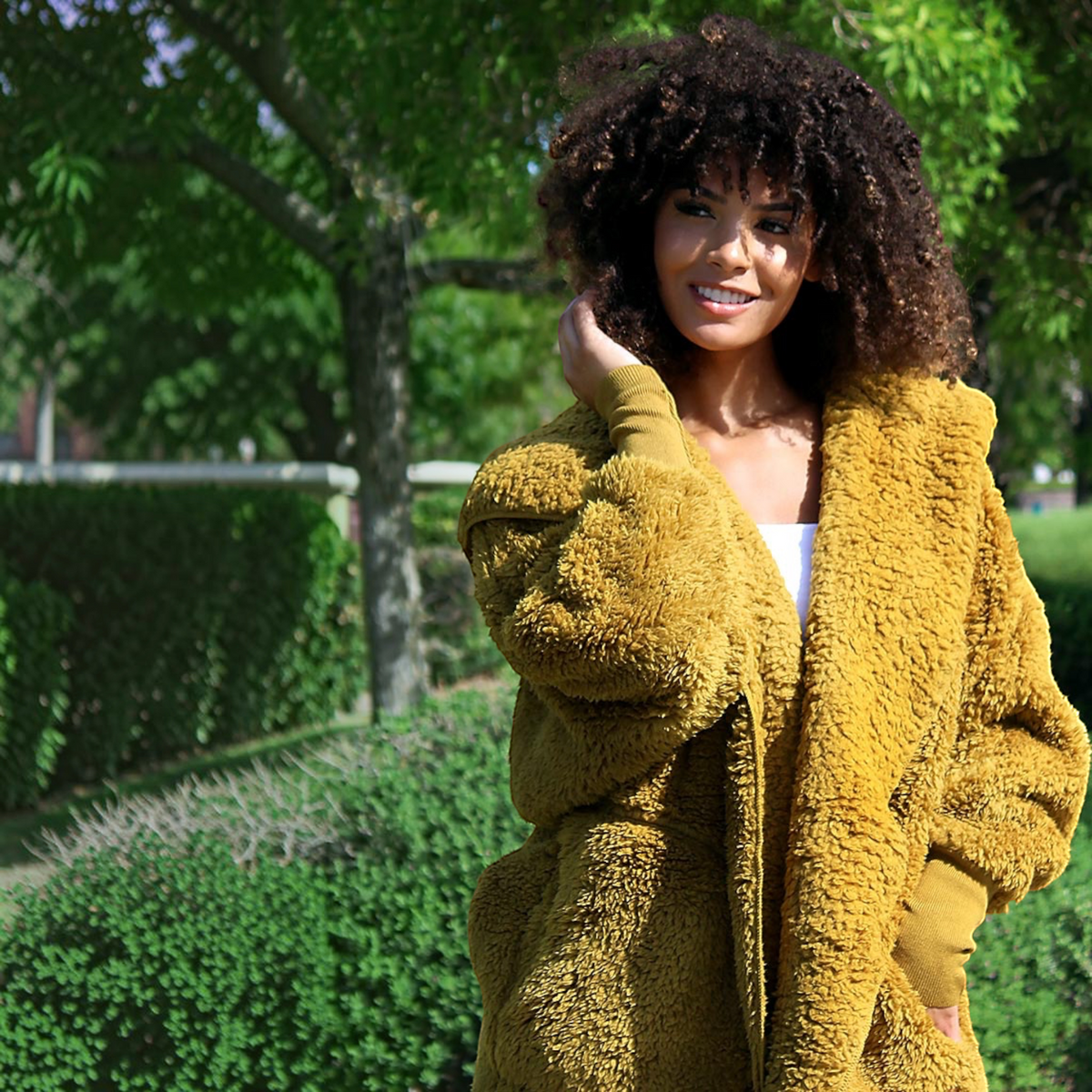 Plum Bottom NORDIC BEACH mustard yellow hooded body wrap in fluffy micro poly fabric worn by a smiling woman outdoors