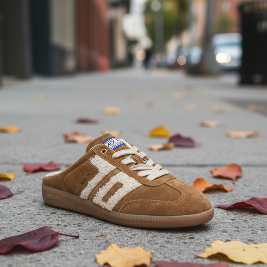 Brown slide sneaker sitting on a sidewalk with leaves.