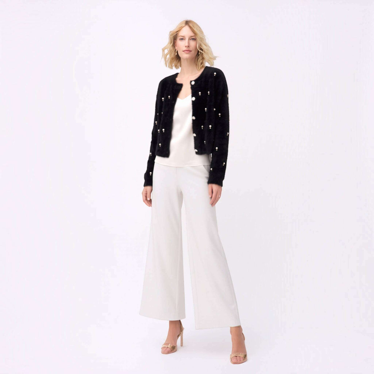 Plum Bottom black fluffy bolero with diamond and pearl embellishments worn over a white top and wide-leg trousers