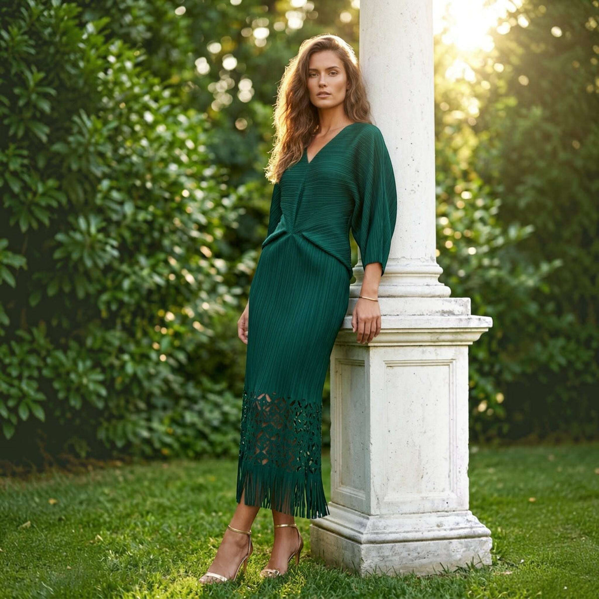 Plum Bottom ELLYNDALE emerald green pleated midi dress with waist cutout and fringe hem worn by a model outdoors.