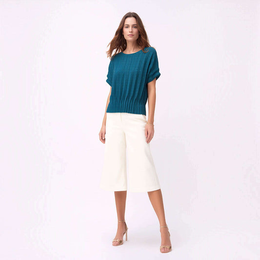 Model wearing a Plum Bottom ELLYNDALE blue pleated short-sleeve top with a dual fold design and white culottes.
