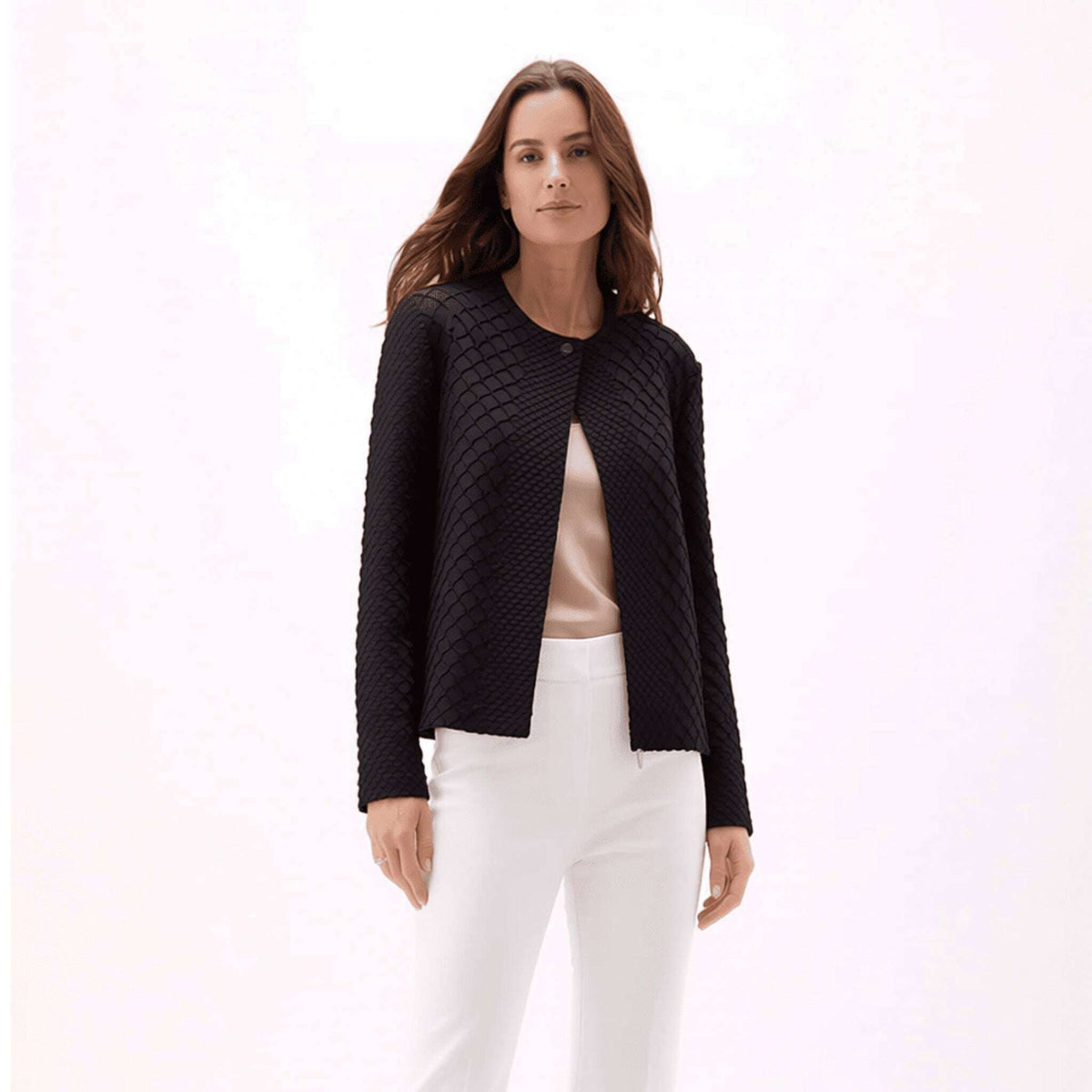 Plum Bottom ELLYNDALE black waffle weave pleated jacket with a round neckline worn over a beige top and white pants.