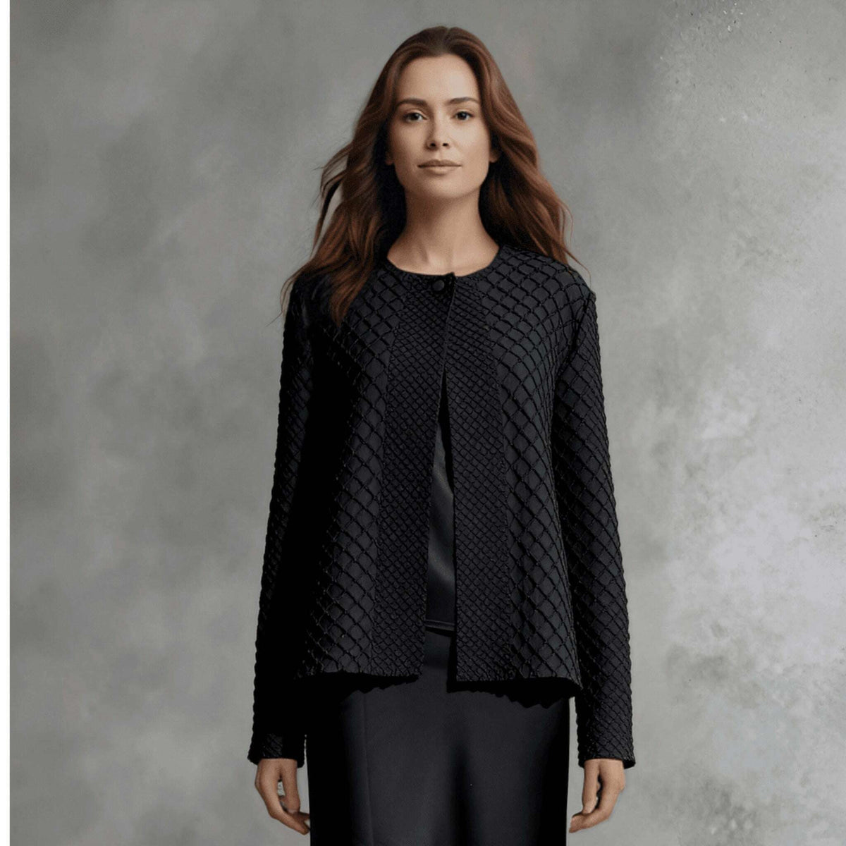 Plum Bottom ELLYNDALE black waffle weave pleated jacket with a round neckline and open front worn over a satin skirt.