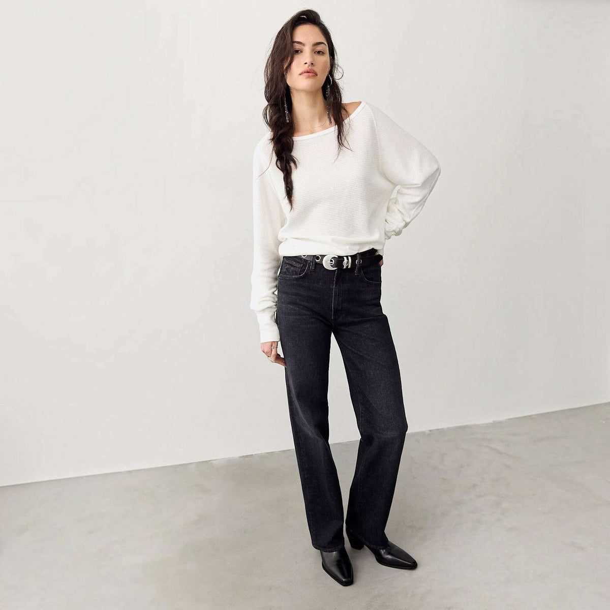 Plum Bottom model wearing a white Free People thermal long sleeve top with a boat neckline and black denim jeans.