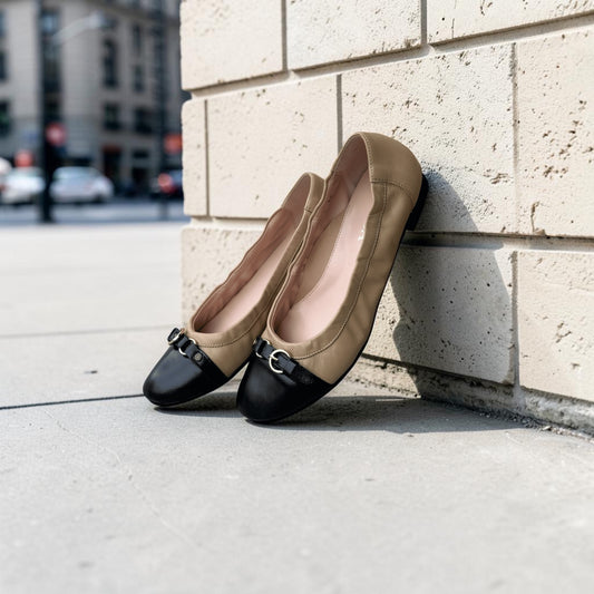 Plum Bottom LA LISA ballet flats in camel and black leather with a gold buckle detail leaning against a brick wall.