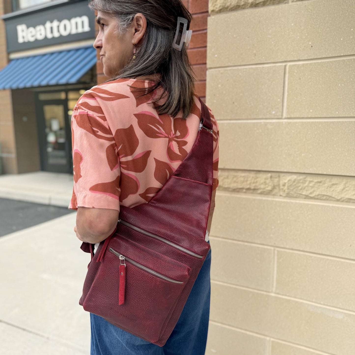 Plum Bottom DANIELLA LEHAVHI Ride red leather sling bag worn crossbody by a woman in a casual outfit
