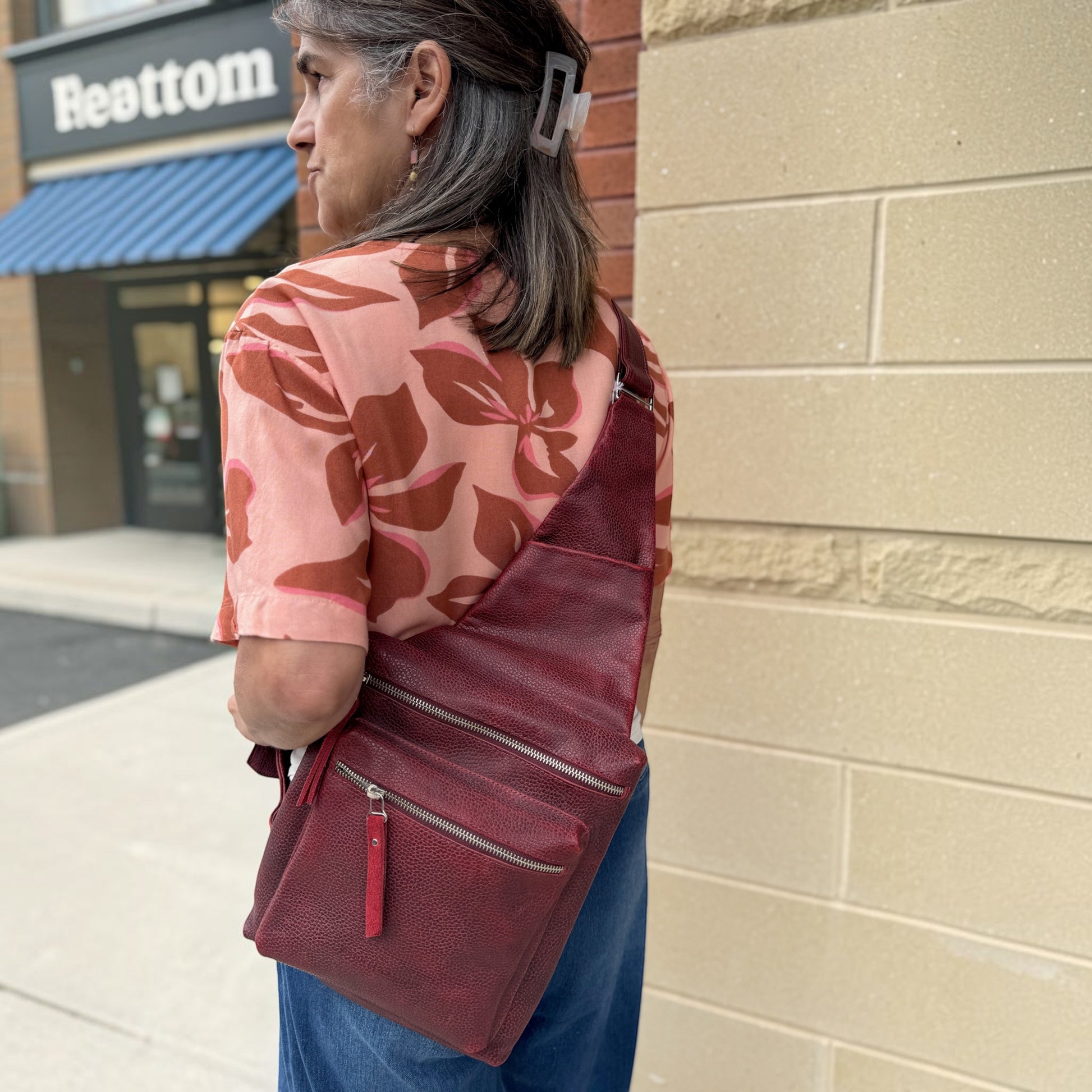 Plum Bottom DANIELLA LEHAVHI Ride red leather sling bag worn crossbody by a woman in a casual outfit