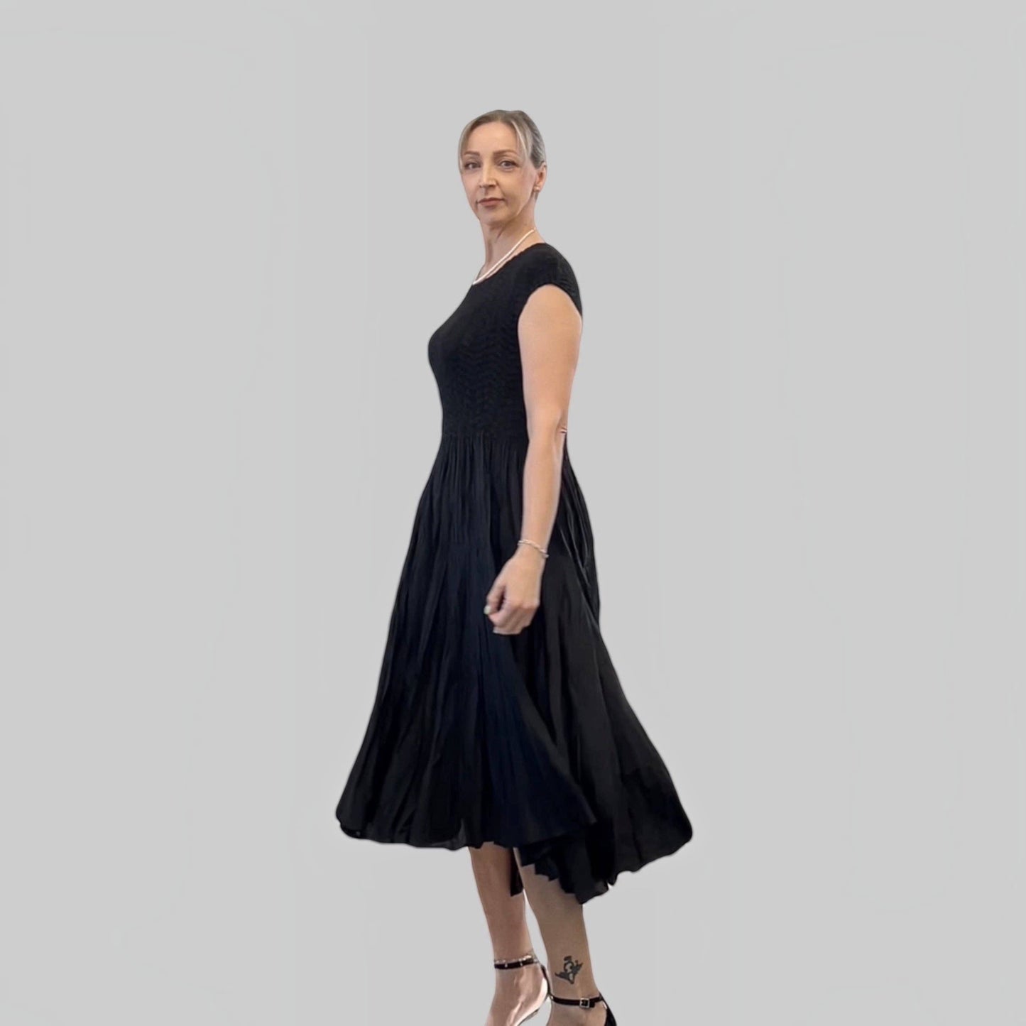 Plum Bottom Ellyndale black pleated midi dress with cupsleeves worn by a model against a neutral background