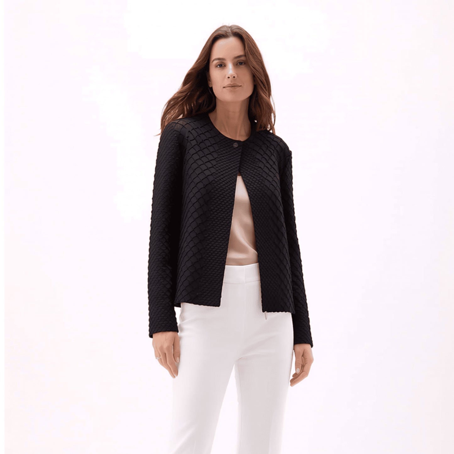 Plum Bottom ELLYNDALE black waffle weave pleated jacket with a round neckline worn over a beige top and white pants.