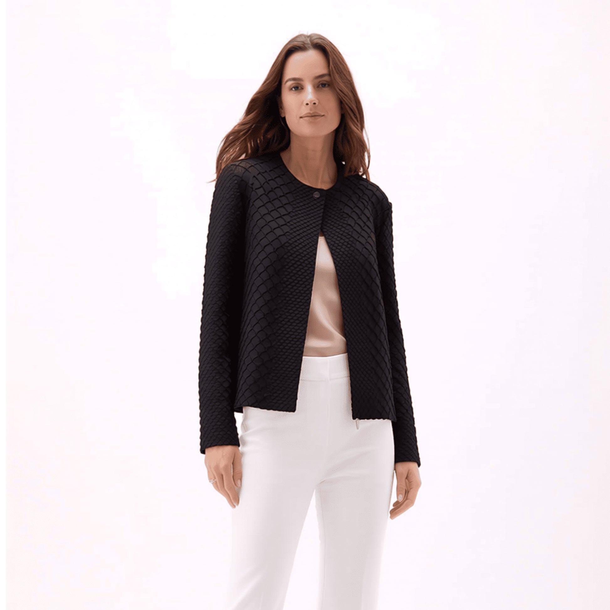 Plum Bottom ELLYNDALE black waffle weave pleated jacket with a round neckline worn over a beige top and white pants.