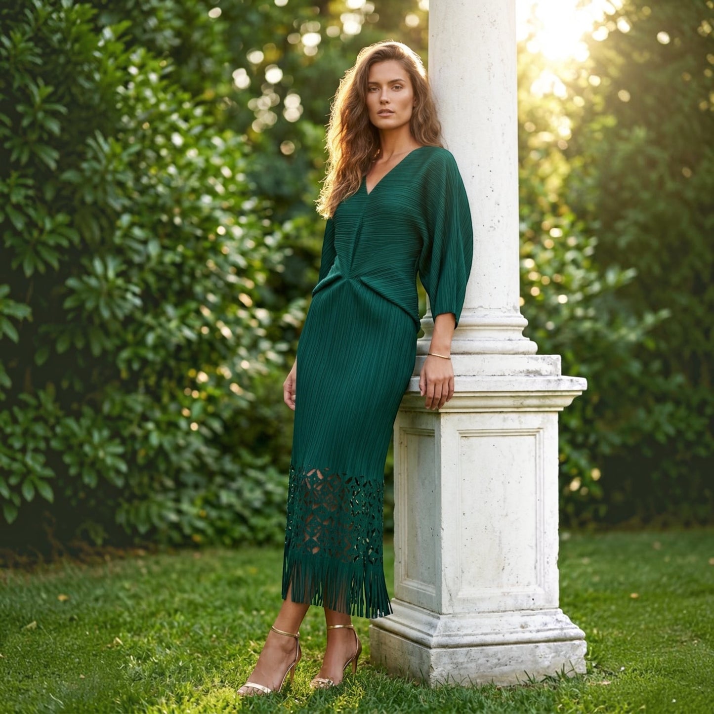 Plum Bottom ELLYNDALE emerald green pleated midi dress with waist cutout and fringe hem worn by a model outdoors.
