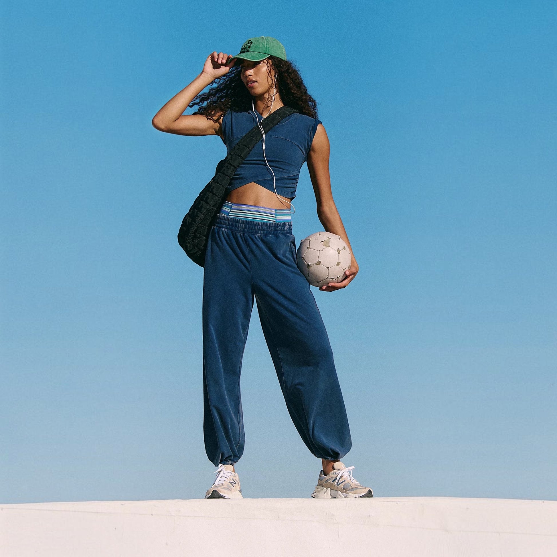 Plum Bottom model wearing a navy blue FREE PEOPLE Hot Shot Crossover set with a cropped top and wide-leg joggers.