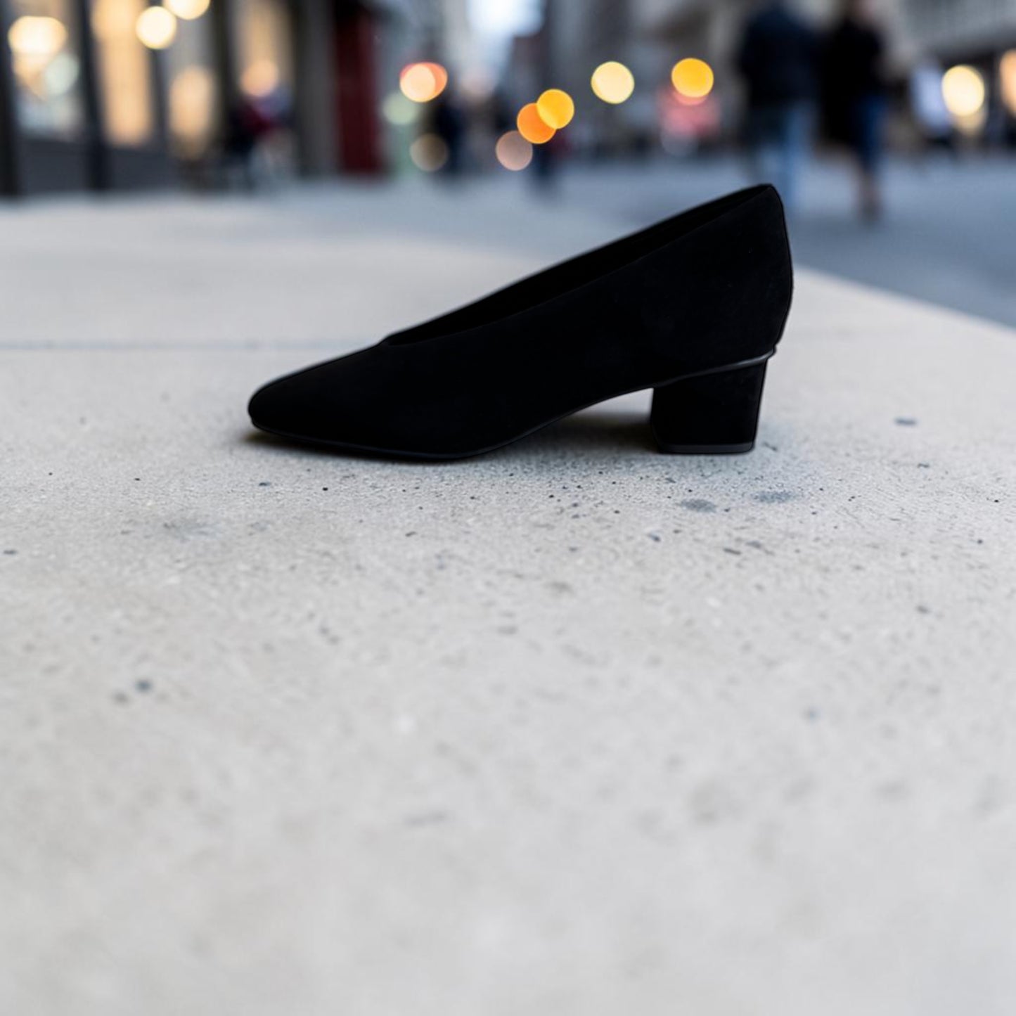 Plum Bottom VANELI Solara black suede pump with a square toe and low block heel on a concrete surface.