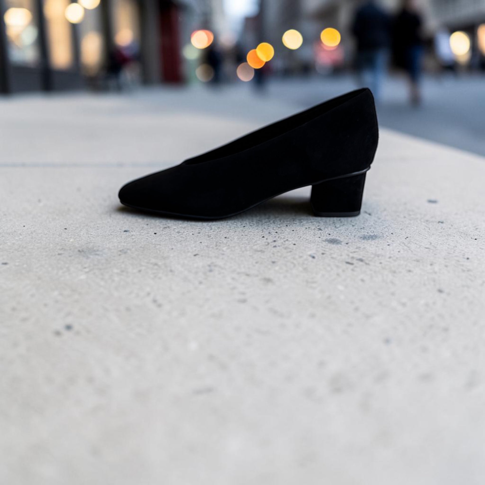 Plum Bottom VANELI Solara black suede pump with a square toe and low block heel on a concrete surface.