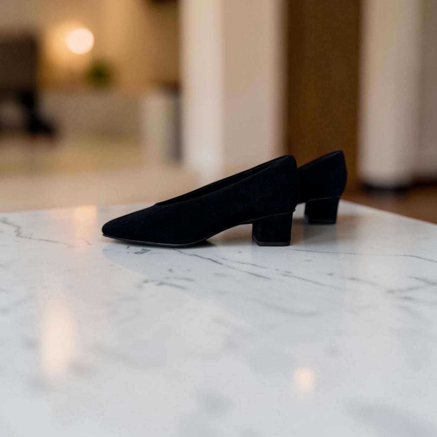 Plum Bottom VANELI Solara black suede square toe block heel pump on a stone ledge