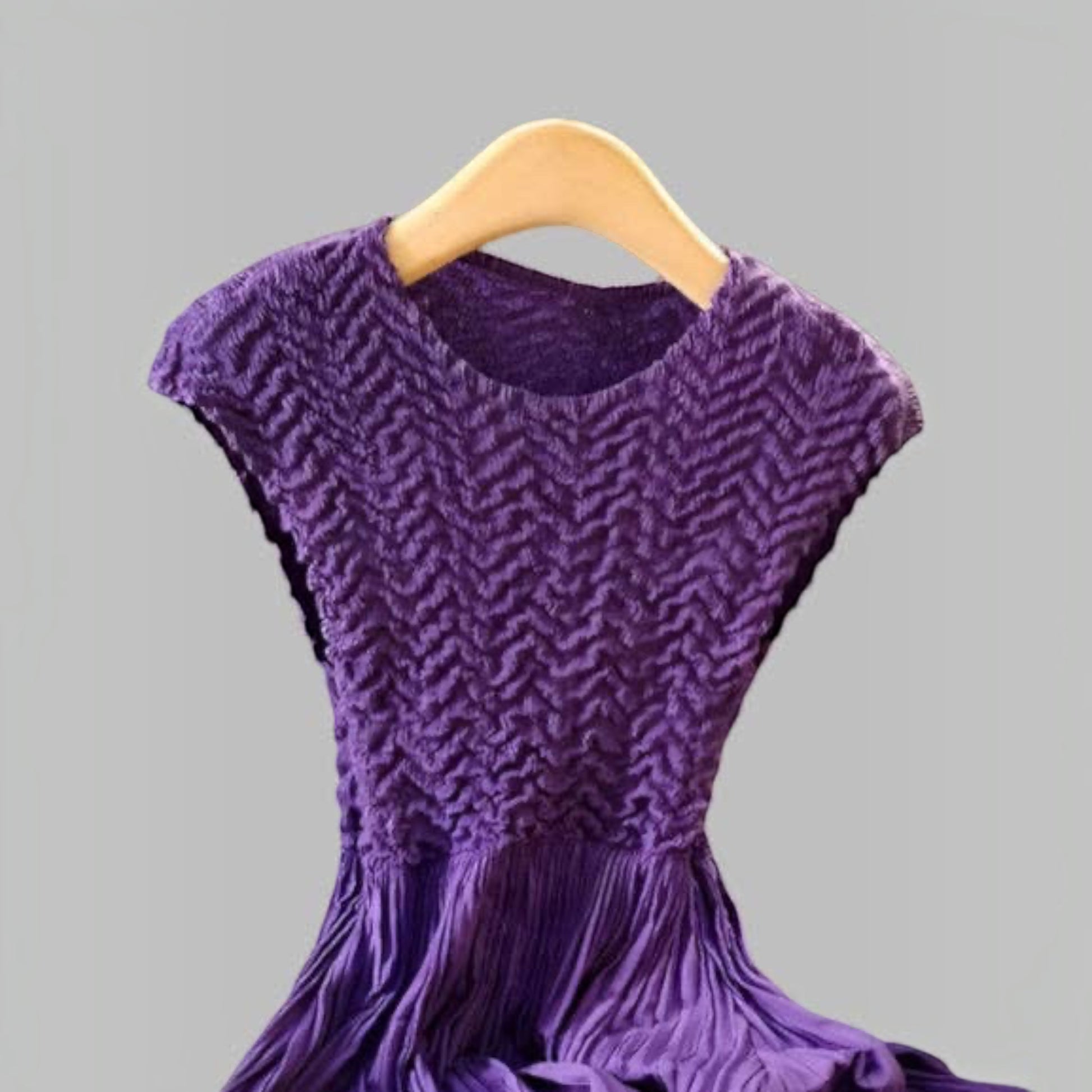 Plum Bottom violet pleated dress with textured bodice and cupsleeves on a wooden hanger
