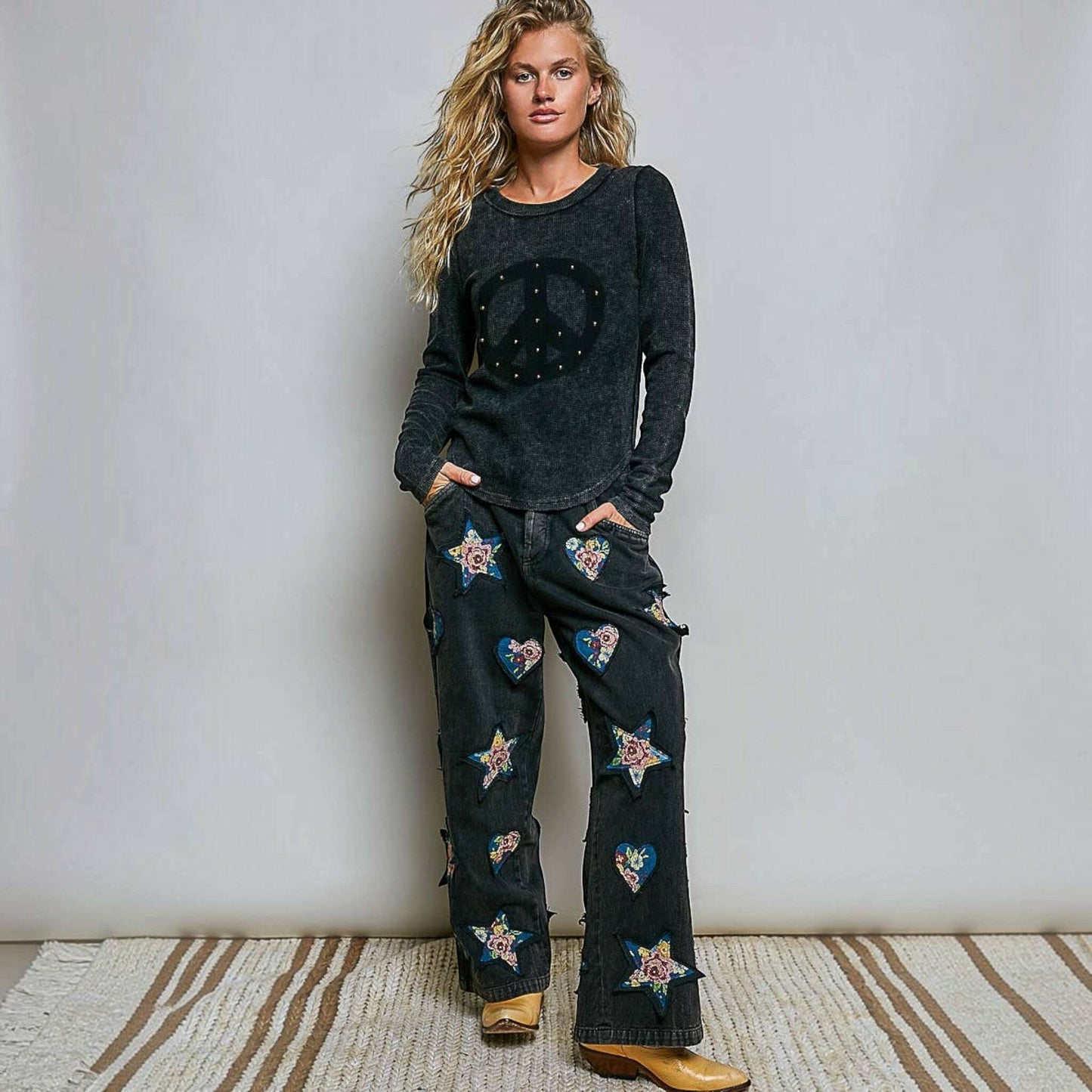 Plum Bottom model wearing a black vintage wash thermal knit top with a peace sign stud design and outseam details.