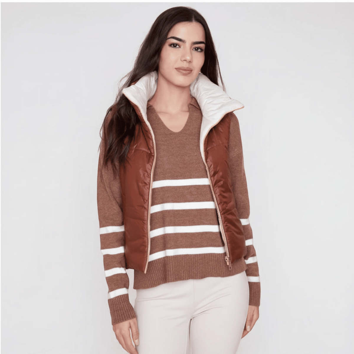 Model wearing a Plum Bottom RENUAR reversible cropped vest in brown and white over a striped sweater