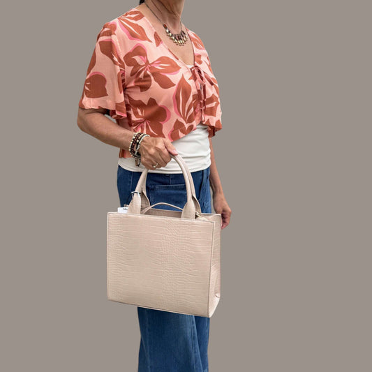 Plum Bottom SONDRA ROBERTS nude crocodile-embossed structured frame bag with dual handles held by a woman
