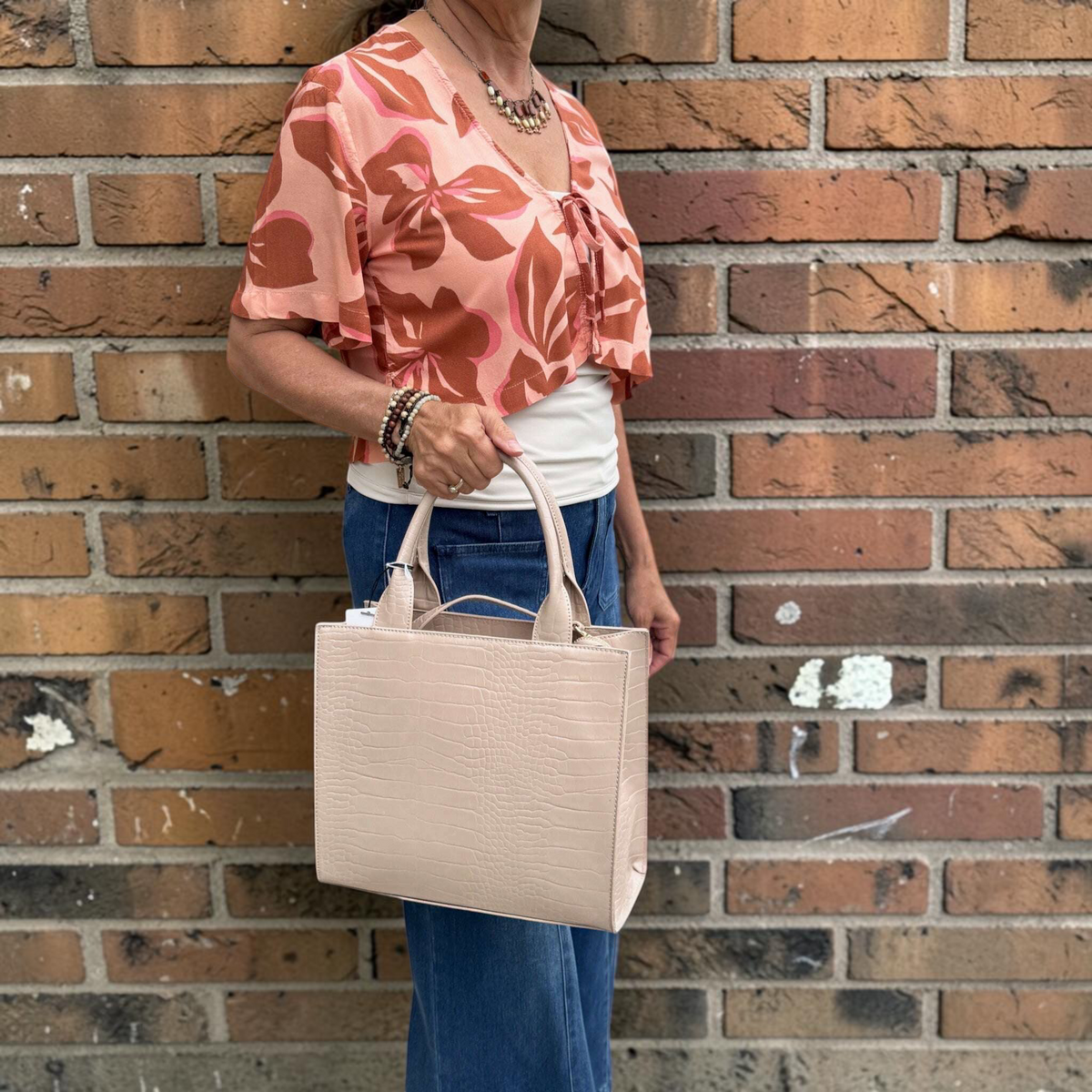 Plum Bottom SONDRA ROBERTS nude crocodile-embossed structured frame bag with dual handles held by a woman