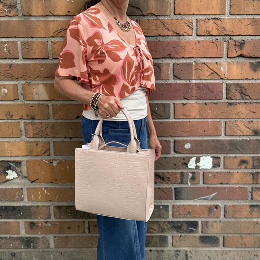 Plum Bottom SONDRA ROBERTS nude crocodile-embossed structured frame bag with dual handles held by a woman