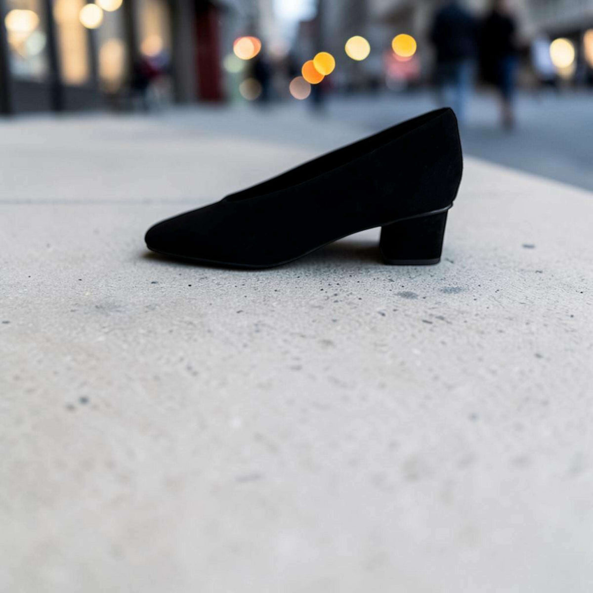 Plum Bottom VANELI Solara black suede pump with a square toe and low block heel on a concrete surface.