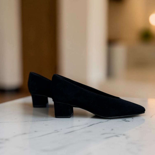 Plum Bottom VANELI Solara black suede square toe block heel pump on a stone ledge